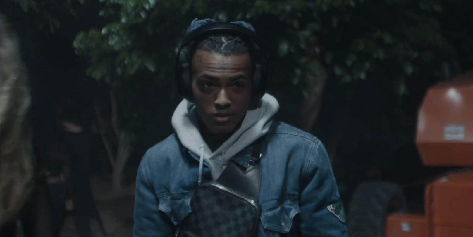 Видео показывает, как рэпер слушает музыку, наблюдая за своими друзьями на вечеринке в лесу